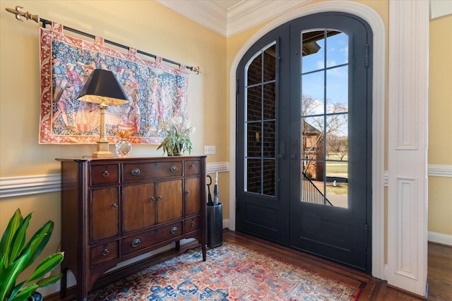 entryway with arched walkways, wood finished floors, crown molding, and french doors