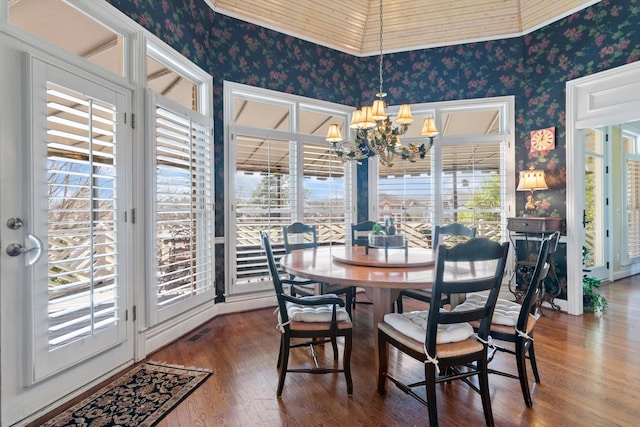 dining space featuring a chandelier, a healthy amount of sunlight, hardwood / wood-style flooring, and wallpapered walls