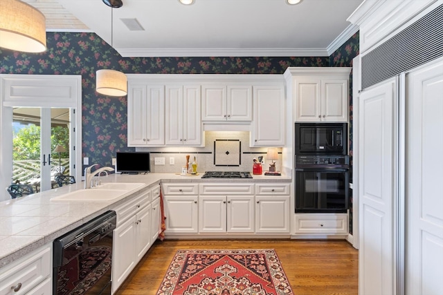 kitchen featuring a sink, black appliances, light wood-style flooring, and wallpapered walls