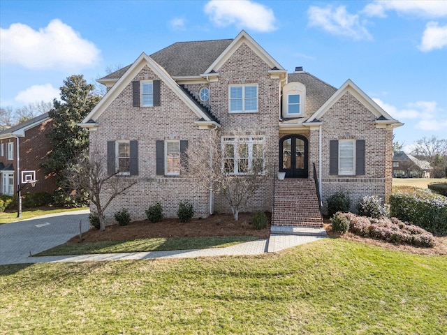 view of front of house featuring french doors, brick siding, and a front lawn