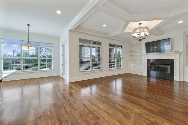 unfurnished living room with a fireplace, wood finished floors, built in features, ornamental molding, and an inviting chandelier