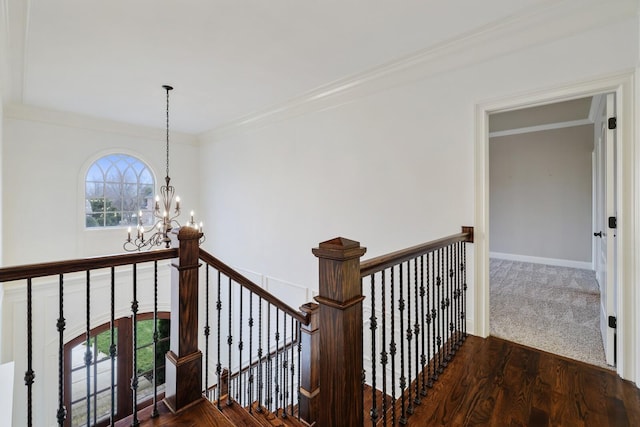 corridor featuring dark wood finished floors, an inviting chandelier, ornamental molding, an upstairs landing, and baseboards