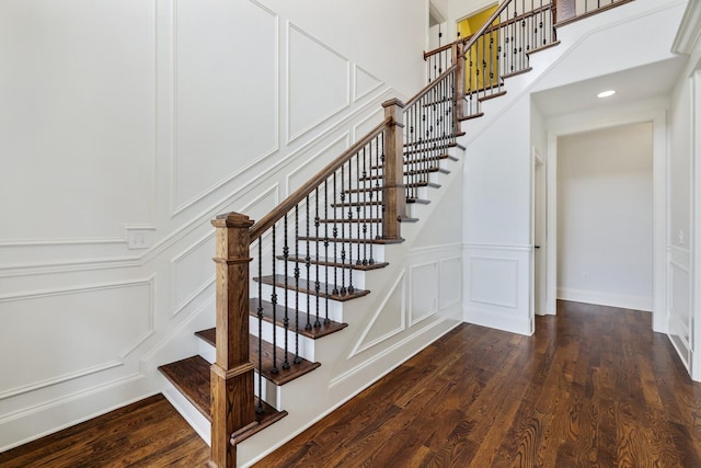 staircase featuring a decorative wall and wood finished floors