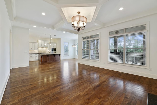 unfurnished living room with dark wood-style floors, coffered ceiling, a notable chandelier, and baseboards