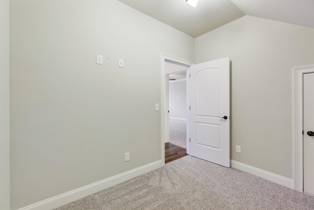 unfurnished bedroom with carpet flooring, vaulted ceiling, and baseboards