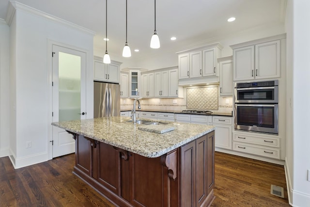 kitchen featuring stainless steel appliances, tasteful backsplash, dark wood-type flooring, and a sink