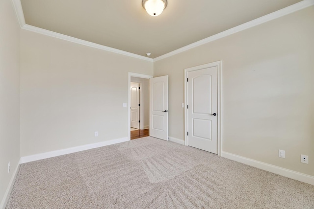 carpeted empty room with crown molding and baseboards