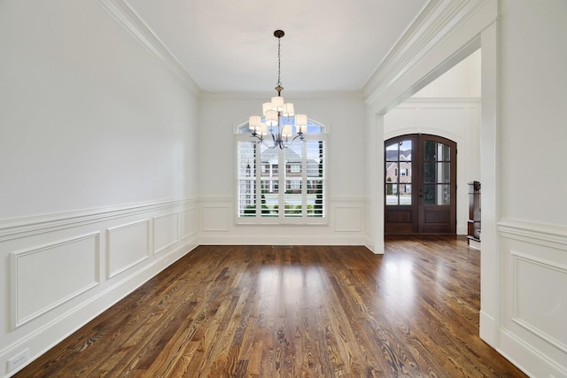 unfurnished dining area featuring ornamental molding, a chandelier, dark wood finished floors, and french doors