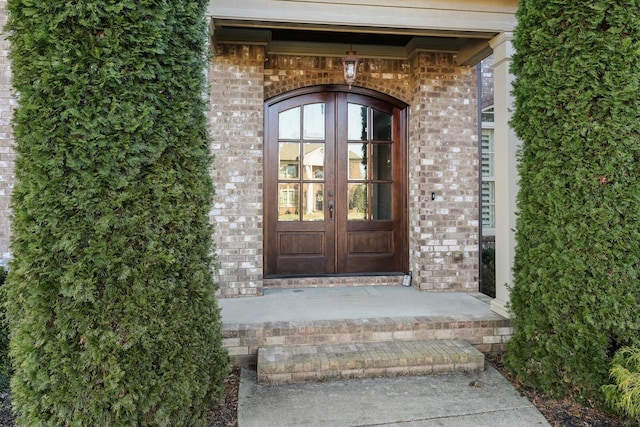 view of exterior entry with french doors and brick siding