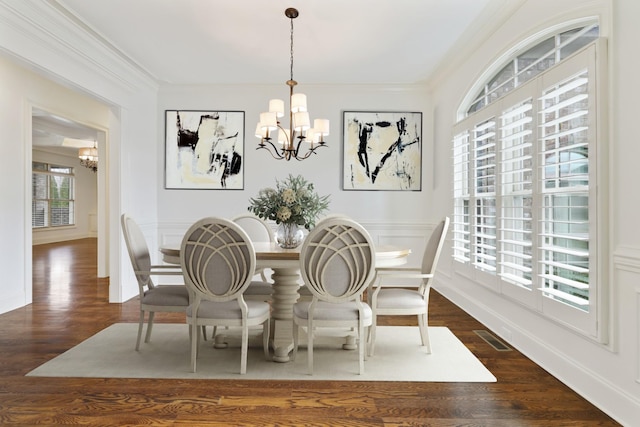 dining area with crown molding, wood finished floors, visible vents, and an inviting chandelier