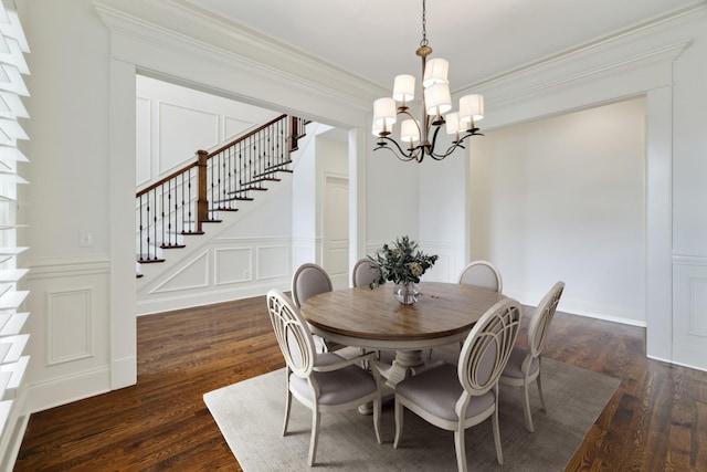 dining room featuring dark wood-style floors, a notable chandelier, a decorative wall, stairway, and ornamental molding