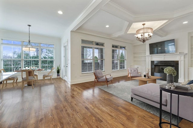 living area with a notable chandelier, coffered ceiling, a fireplace, wood finished floors, and built in features