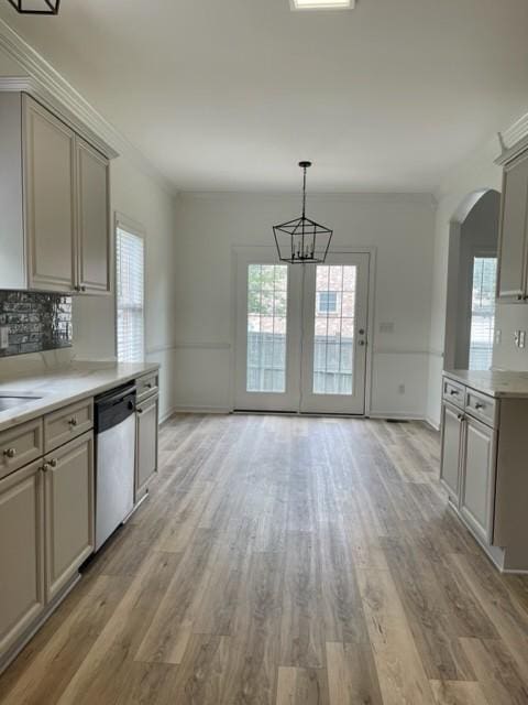 kitchen with arched walkways, light countertops, stainless steel dishwasher, decorative backsplash, and light wood finished floors