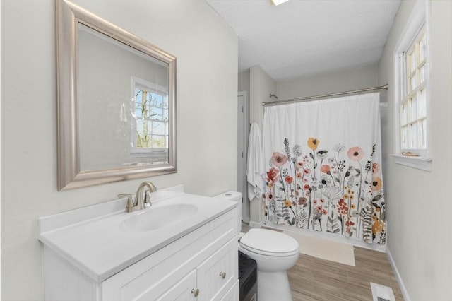 bathroom with toilet, a shower with shower curtain, wood finished floors, and visible vents