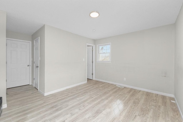 empty room featuring light wood-type flooring and baseboards