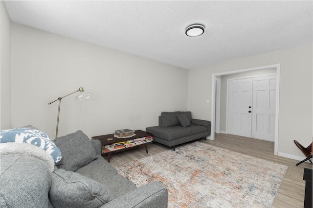 living area featuring a textured ceiling, baseboards, and wood finished floors