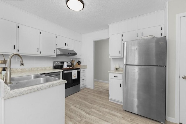 kitchen featuring light wood-style flooring, appliances with stainless steel finishes, light countertops, under cabinet range hood, and a sink