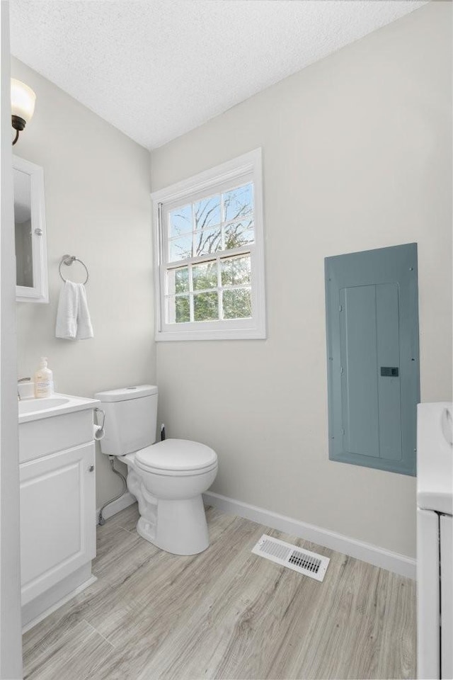 bathroom with visible vents, toilet, vanity, and electric panel