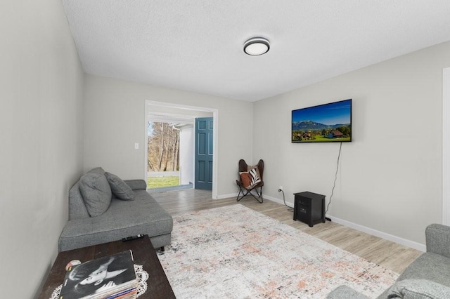 living area with light wood-style flooring, baseboards, and a textured ceiling