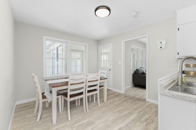 dining room with light wood-style floors, a textured ceiling, and baseboards