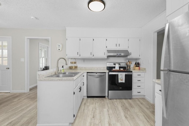 kitchen with light countertops, appliances with stainless steel finishes, a sink, a peninsula, and under cabinet range hood