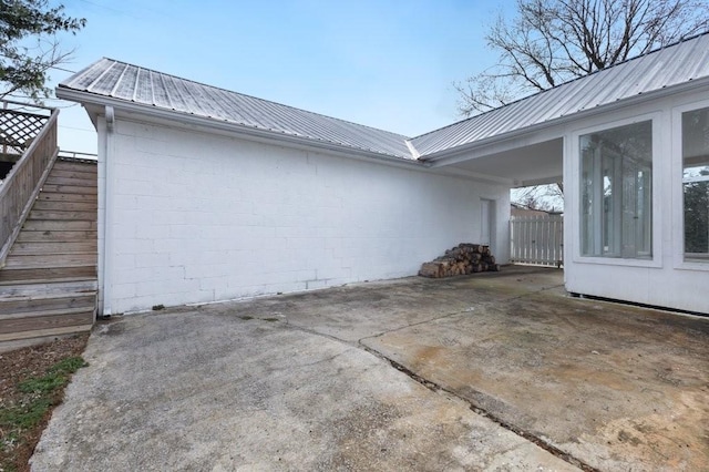 view of home's exterior with stairs, metal roof, a patio area, and driveway