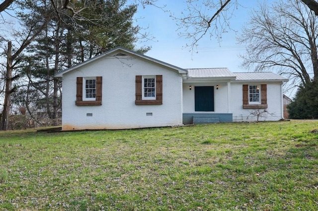 view of front facade with crawl space, a front yard, metal roof, and brick siding