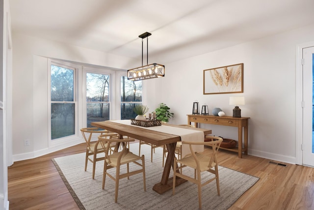 dining space with light wood-type flooring, baseboards, and visible vents