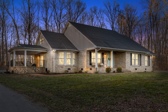 view of front of property with a yard, a porch, crawl space, and brick siding