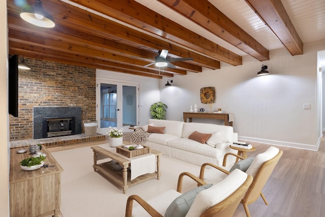 living room with beamed ceiling, a brick fireplace, wood finished floors, and baseboards