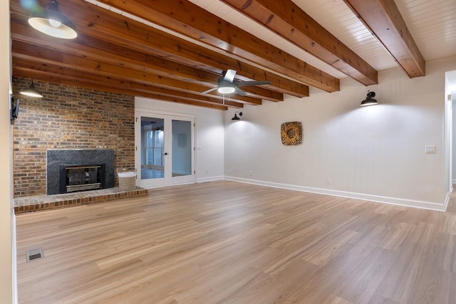 unfurnished living room featuring visible vents, a fireplace, baseboards, and wood finished floors