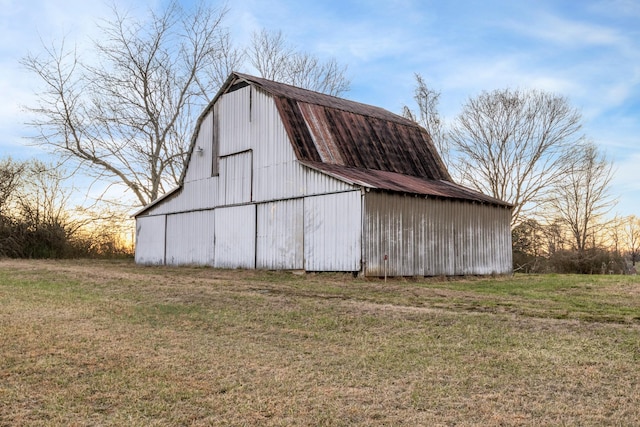 outdoor structure at dusk with a barn, a lawn, and an outbuilding