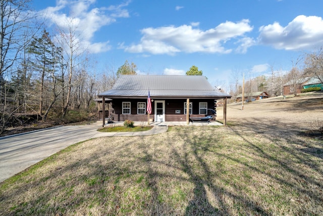 view of front of home featuring covered porch, metal roof, and a front lawn