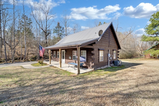 view of side of property with central air condition unit, a patio area, metal roof, and a lawn