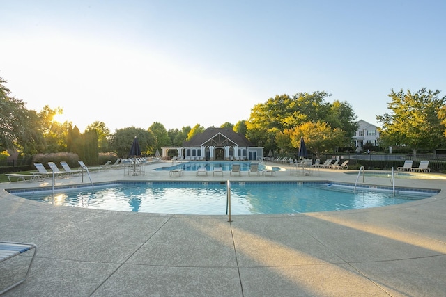 community pool with a patio area and fence