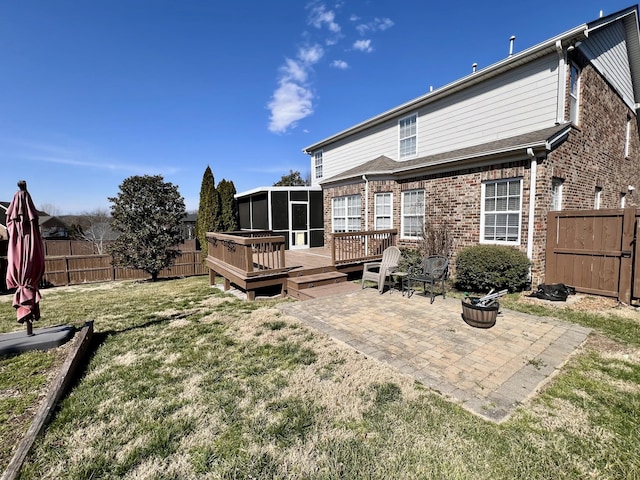 rear view of property featuring a patio, a sunroom, a fenced backyard, a deck, and brick siding