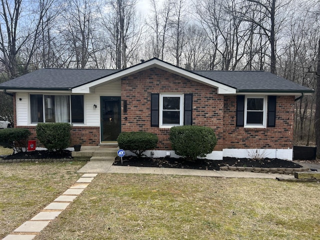 ranch-style home with a shingled roof, brick siding, and a front lawn