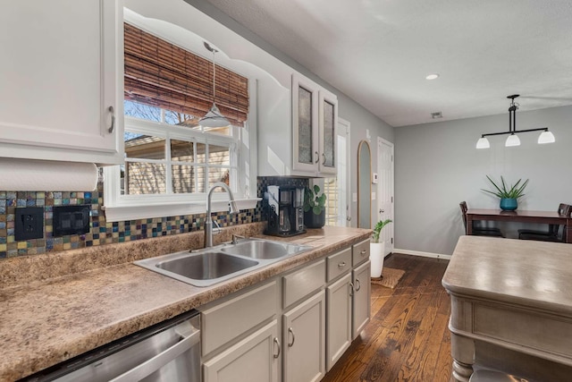 kitchen featuring dishwasher, dark wood-style flooring, a sink, and pendant lighting