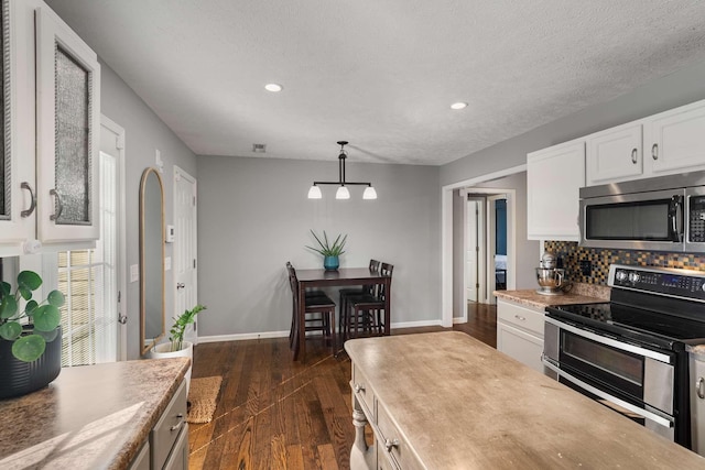 kitchen featuring baseboards, dark wood-style flooring, stainless steel appliances, white cabinetry, and backsplash