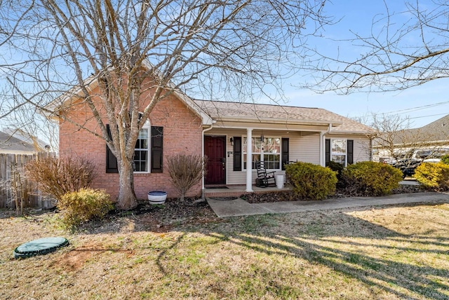 view of front of property featuring a porch, a front yard, and brick siding