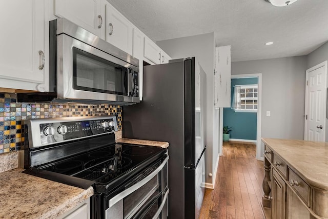 kitchen featuring hardwood / wood-style floors, white cabinetry, stainless steel appliances, and backsplash