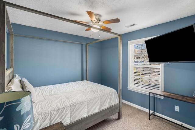 carpeted bedroom featuring a textured ceiling, ceiling fan, visible vents, and baseboards