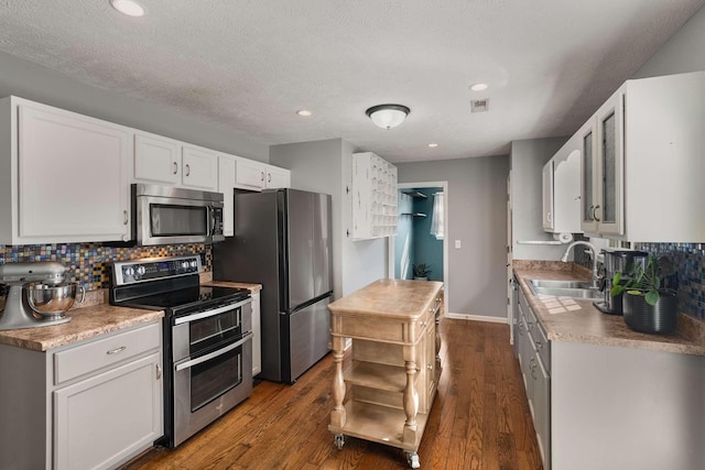 kitchen featuring decorative backsplash, dark wood-style floors, stainless steel appliances, white cabinetry, and a sink