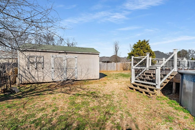 view of yard featuring a storage shed, fence, a deck, and an outbuilding