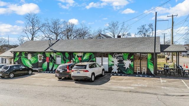 view of front facade with uncovered parking and roof with shingles