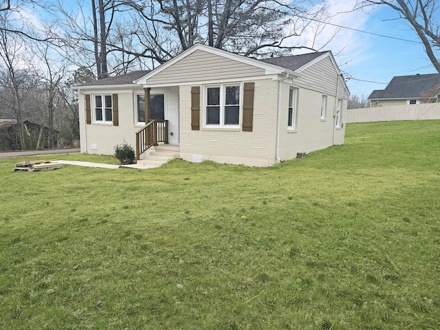 view of front of home with brick siding, fence, roof with shingles, crawl space, and a front yard