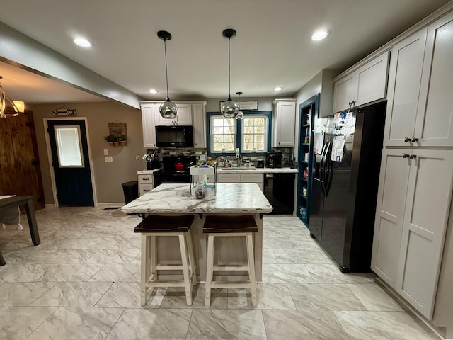 kitchen with a kitchen island, a kitchen breakfast bar, light stone countertops, marble finish floor, and black appliances