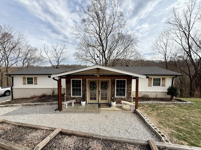 view of front of property with brick siding, a shingled roof, board and batten siding, and french doors