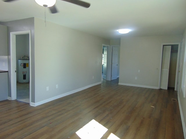 unfurnished bedroom with ceiling fan, wood finished floors, electric water heater, and baseboards