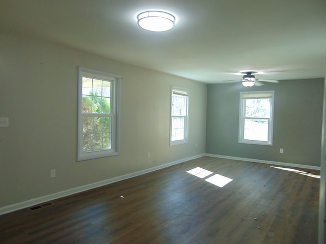 spare room featuring dark wood-style flooring, a healthy amount of sunlight, and baseboards